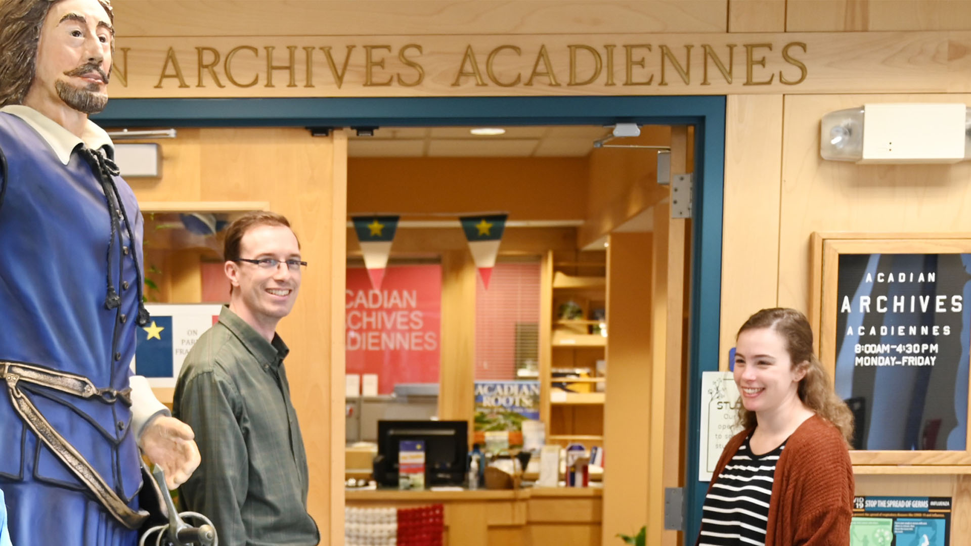 A man and woman at a door with the inscription Acadian Archives.