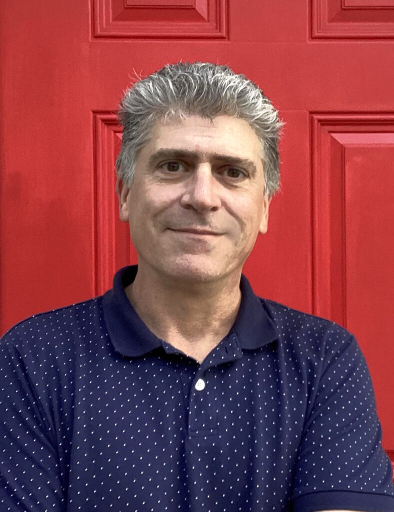 Man in blue shirt in front of red door.